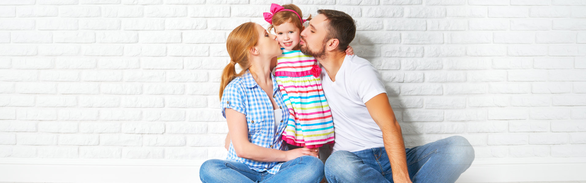 parents kissing young child